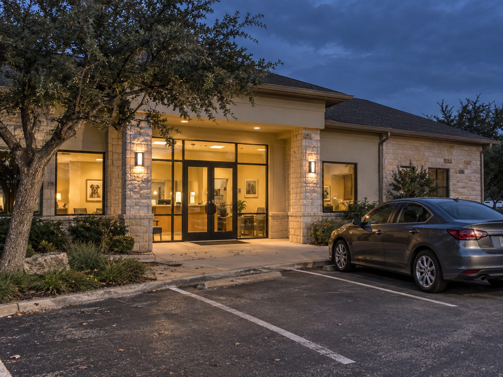 Entrance of a single-story veterinary clinic at dusk with lights on inside and one car parked out front